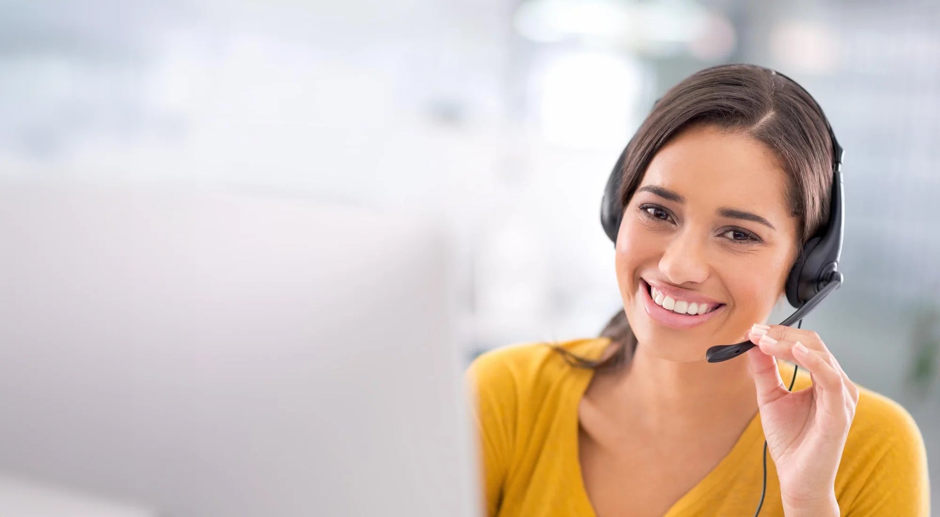 Une agente du service client, souriante et portant un casque, est prête à répondre aux questions des clients.